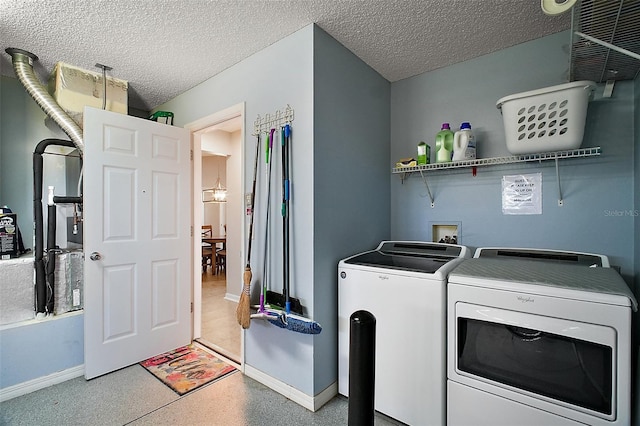 clothes washing area featuring baseboards, a textured ceiling, washing machine and dryer, and laundry area