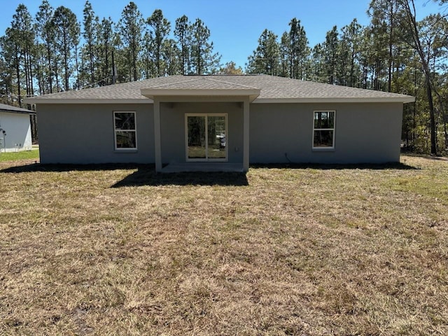 back of property featuring stucco siding and a yard