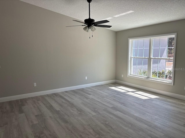 empty room featuring a ceiling fan, wood finished floors, baseboards, and a textured ceiling