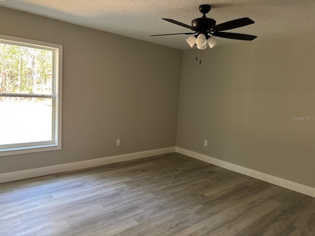 empty room with ceiling fan, baseboards, dark wood-style flooring, and a textured ceiling