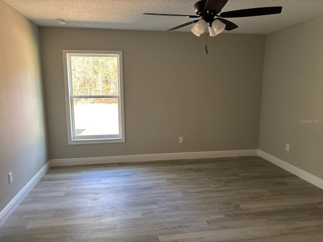 empty room with baseboards, a textured ceiling, and wood finished floors