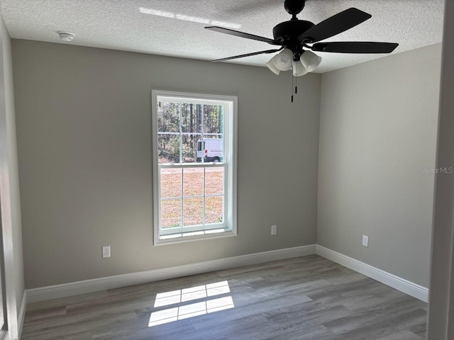 empty room with plenty of natural light, wood finished floors, and baseboards