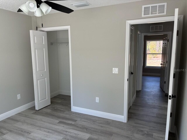 unfurnished bedroom featuring visible vents, baseboards, and wood finished floors