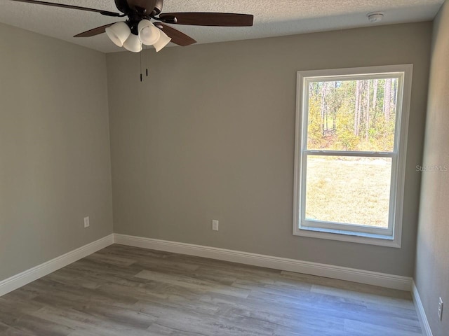 spare room featuring wood finished floors, baseboards, and a textured ceiling