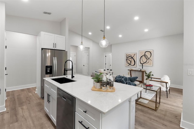 kitchen with visible vents, a center island with sink, a sink, white cabinetry, and stainless steel appliances