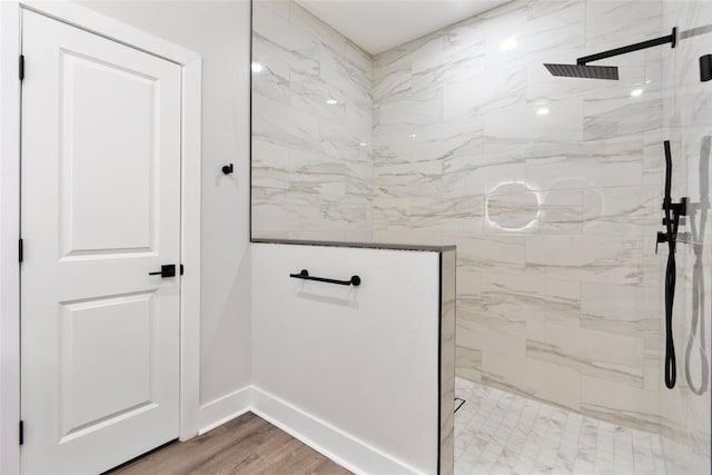 full bath with a marble finish shower, baseboards, and wood finished floors