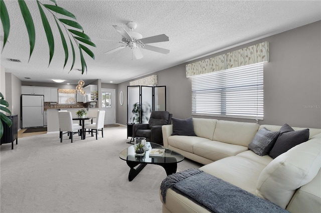 living area with visible vents, light carpet, plenty of natural light, and ceiling fan