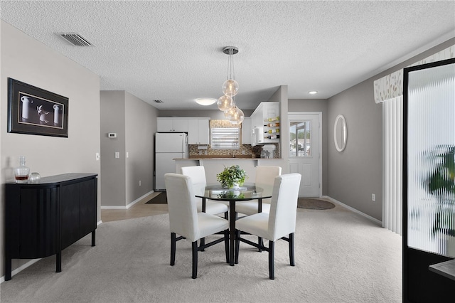 dining area with visible vents, light colored carpet, a textured ceiling, and baseboards