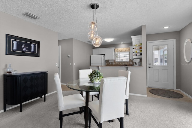 dining space featuring visible vents, baseboards, light colored carpet, and a textured ceiling