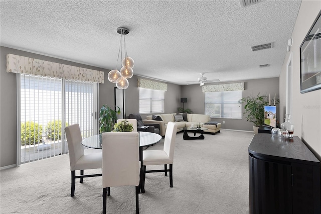 carpeted dining room featuring visible vents, a healthy amount of sunlight, baseboards, and ceiling fan