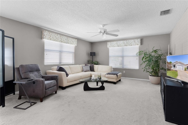 carpeted living area featuring a wealth of natural light, visible vents, baseboards, and a ceiling fan