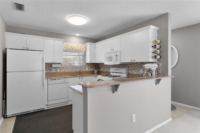 kitchen featuring visible vents, a sink, open shelves, white appliances, and a peninsula