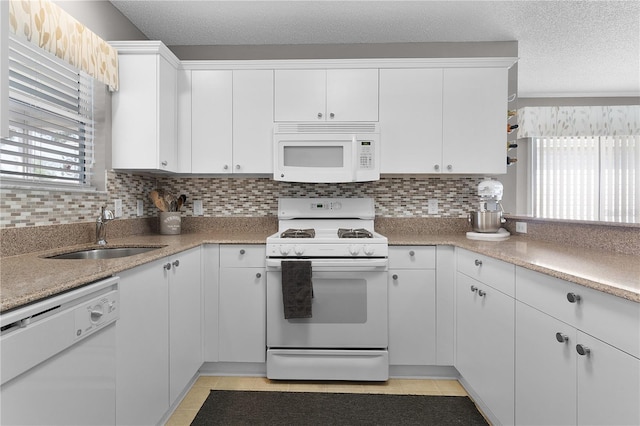 kitchen featuring backsplash, white cabinetry, white appliances, a textured ceiling, and a sink