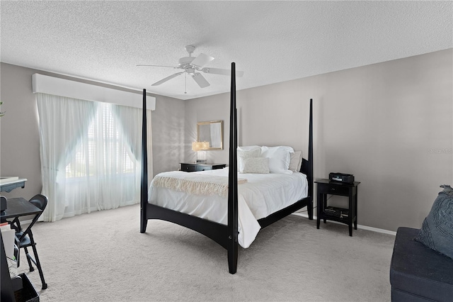 bedroom with baseboards, light colored carpet, a ceiling fan, and a textured ceiling