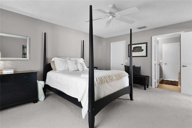 bedroom with a ceiling fan, light colored carpet, visible vents, and a textured ceiling