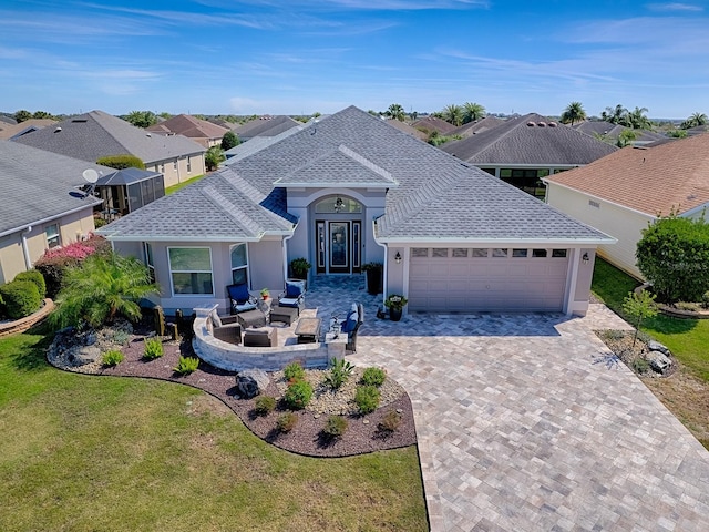 view of front facade featuring a front yard, roof with shingles, an attached garage, stucco siding, and decorative driveway