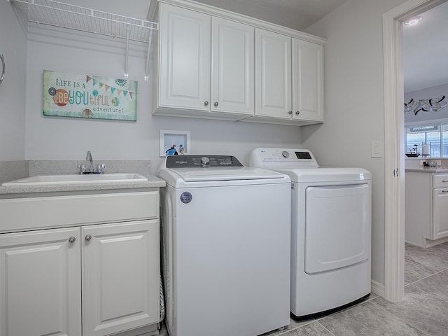 laundry room with washing machine and clothes dryer, cabinet space, and a sink