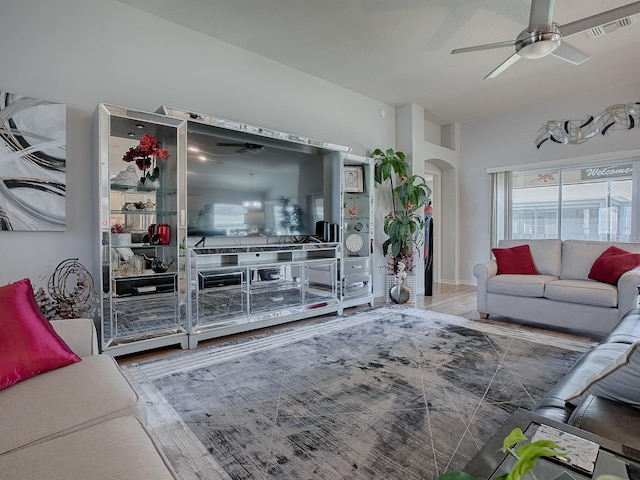 living area featuring visible vents, arched walkways, wood finished floors, and a ceiling fan