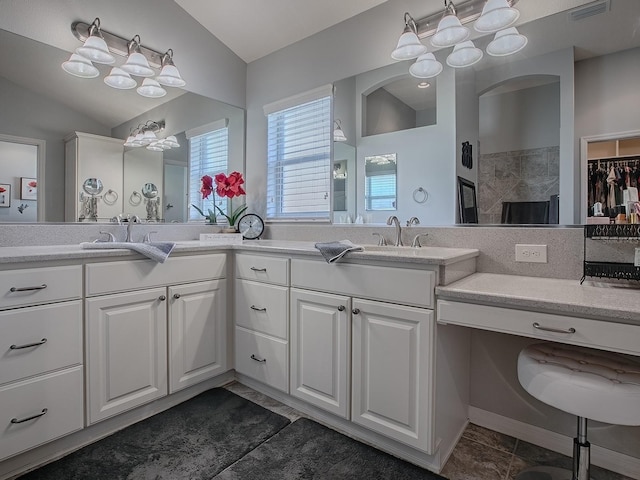 full bath featuring double vanity, visible vents, an inviting chandelier, and vaulted ceiling