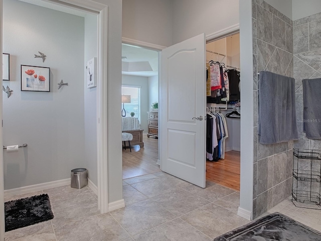 bathroom with a spacious closet, tile patterned floors, and baseboards