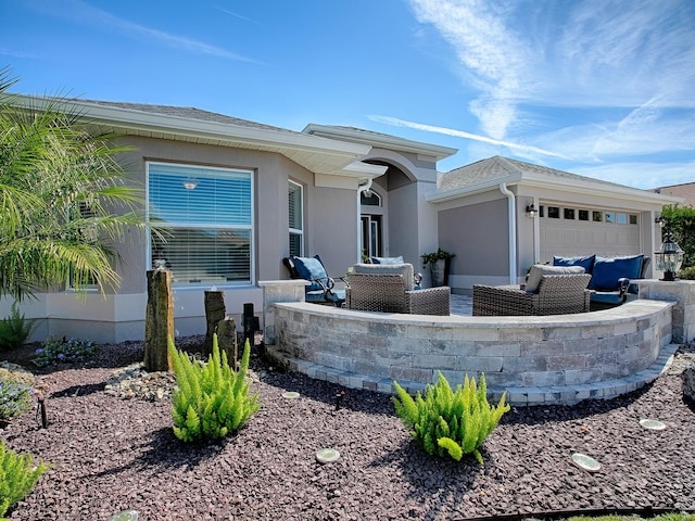 exterior space with outdoor lounge area, an attached garage, and stucco siding