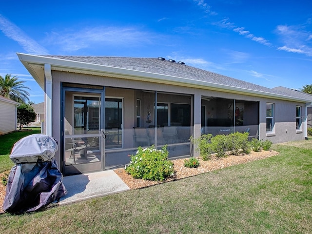 rear view of property with stucco siding, a lawn, roof with shingles, and a sunroom