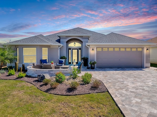 ranch-style home featuring an outdoor living space, stucco siding, an attached garage, and decorative driveway