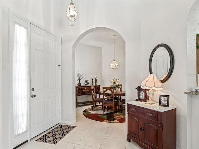 entrance foyer with a chandelier, arched walkways, and light tile patterned floors