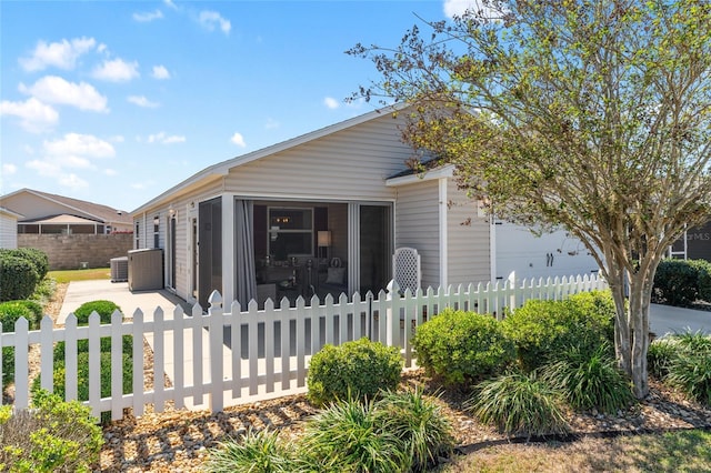 view of front of property featuring a fenced front yard, central air condition unit, and an attached garage