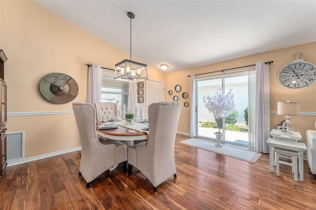 dining area featuring wood finished floors, visible vents, lofted ceiling, and a chandelier