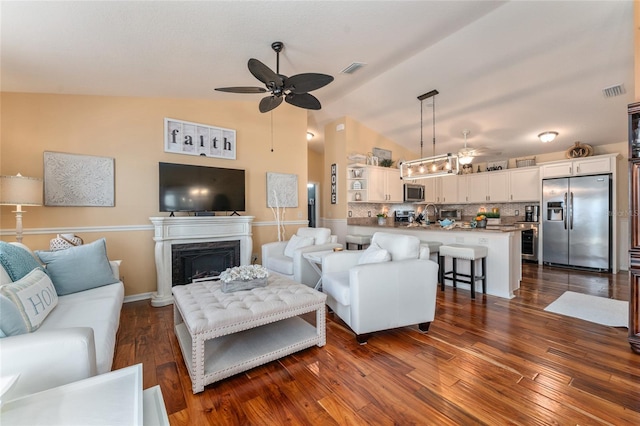 living room featuring dark wood finished floors, vaulted ceiling, a premium fireplace, and ceiling fan