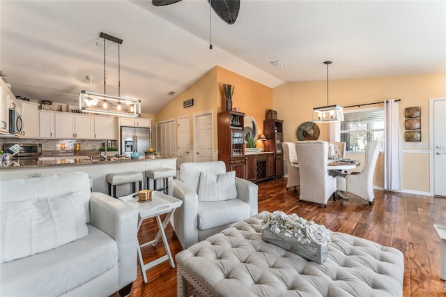 living area with lofted ceiling, a ceiling fan, dark wood-type flooring, and visible vents