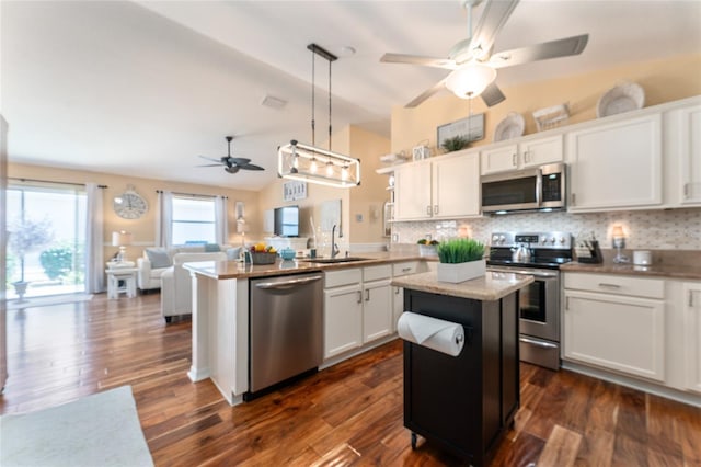 kitchen featuring appliances with stainless steel finishes, a peninsula, white cabinets, a ceiling fan, and a sink