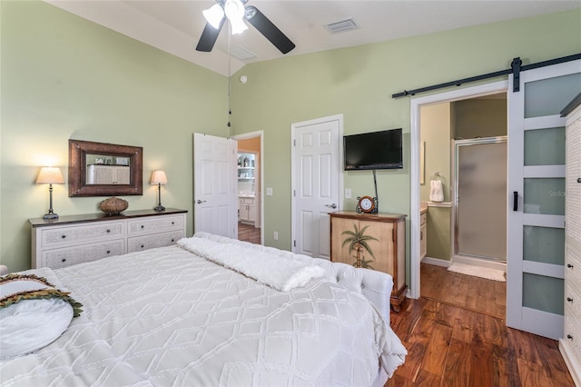 bedroom featuring visible vents, dark wood finished floors, connected bathroom, a barn door, and lofted ceiling