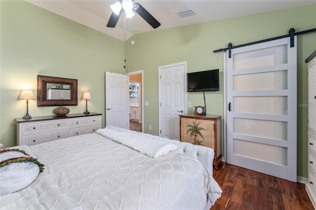 bedroom featuring visible vents, a ceiling fan, wood finished floors, a barn door, and lofted ceiling