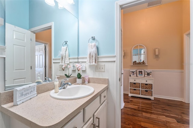 bathroom with visible vents, a wainscoted wall, wood finished floors, and vanity