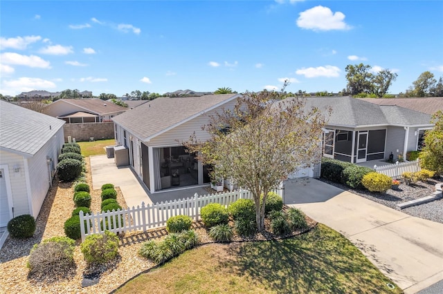 view of front of property with a fenced front yard, cooling unit, driveway, and a sunroom