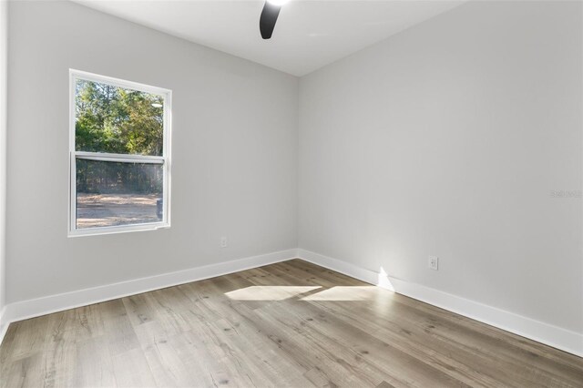 empty room with ceiling fan, baseboards, and wood finished floors