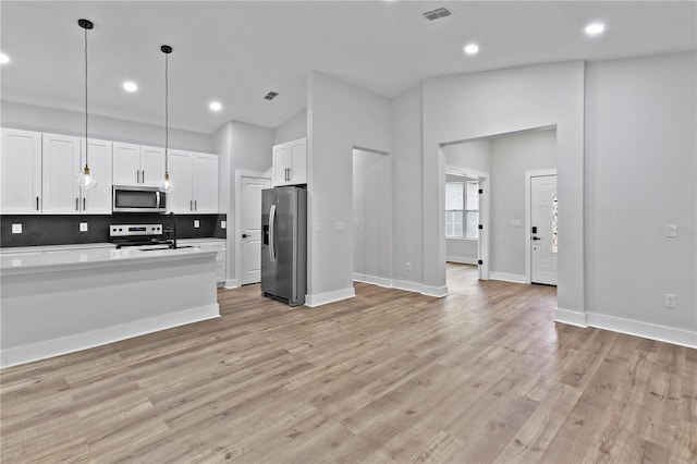 12444 SW 76th Ln, Dunnellon, FL 34432 - kitchen with appliances with stainless steel finishes, white cabinetry, decorative backsplash, light wood-style flooring, and recessed lighting