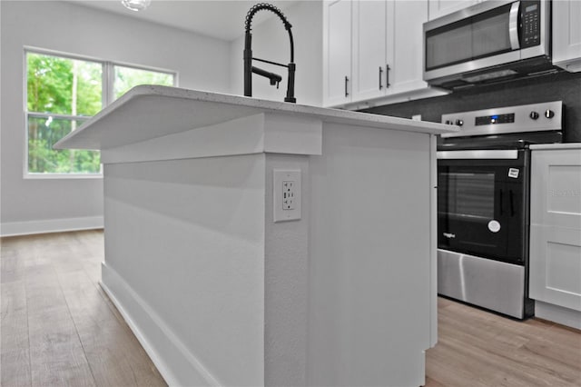 12444 SW 76th Ln, Dunnellon, FL 34432 - kitchen with appliances with stainless steel finishes, white cabinetry, and light wood-style flooring