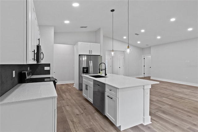 12444 SW 76th Ln, Dunnellon, FL 34432 - kitchen with stainless steel appliances, vaulted ceiling, white cabinetry, light wood-type flooring, and decorative light fixtures