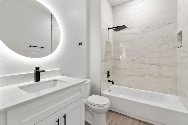 bathroom with vanity, wood finished floors, shower / bathing tub combination, toilet, and a textured wall