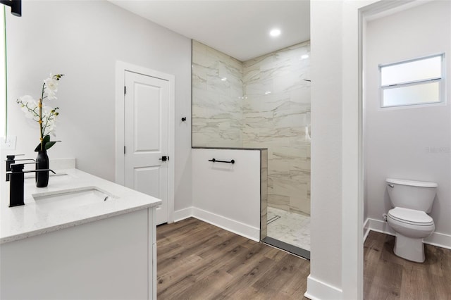 bathroom with a marble finish shower, baseboards, toilet, wood finished floors, and a sink