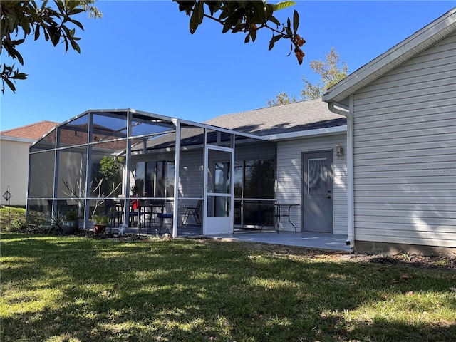 back of property featuring glass enclosure, a patio, a lawn, and roof with shingles