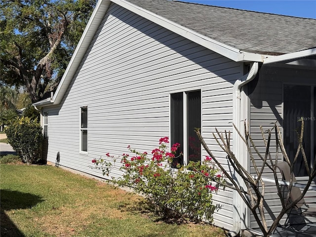 view of property exterior featuring a yard and roof with shingles