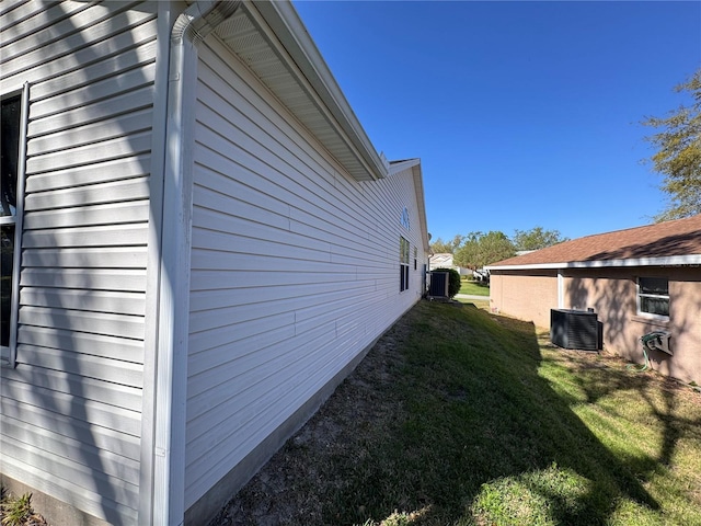 view of side of property featuring central air condition unit and a yard