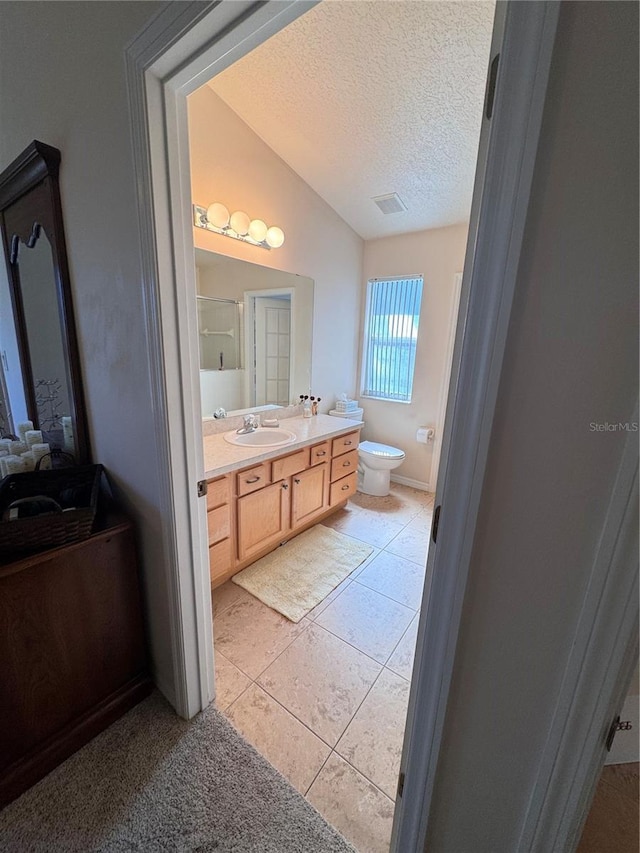 bathroom featuring toilet, vanity, lofted ceiling, tile patterned floors, and a textured ceiling