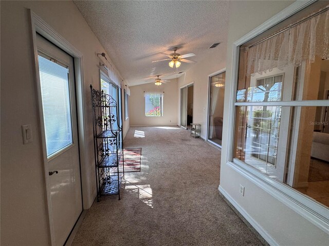 corridor with visible vents, baseboards, vaulted ceiling, carpet floors, and a textured ceiling