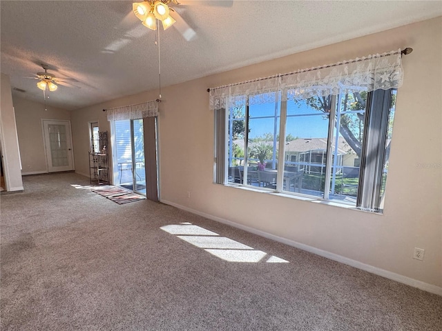 unfurnished room with a ceiling fan, baseboards, carpet floors, vaulted ceiling, and a textured ceiling