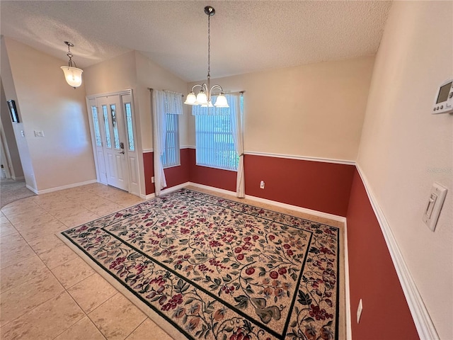 entryway with tile patterned floors, lofted ceiling, a textured ceiling, baseboards, and a chandelier